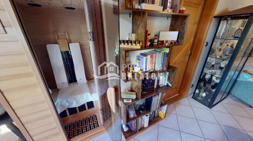 Wooden built-in shelf filled with books, figurines, and small decor items beside a glass cabinet in a cozy living area.