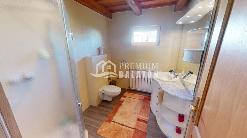 Small modern bathroom with shower enclosure, toilet, and curved marble sink vanity; orange bath rug and window above the radiator.