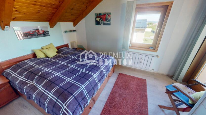 Attic bedroom with a wooden slanted ceiling, a bed with a blue plaid duvet and yellow pillows, and car-themed wall art.