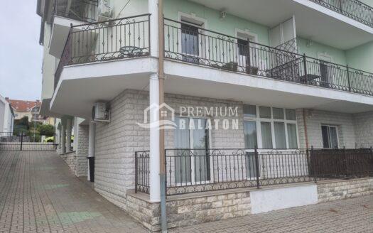 Exterior view of a pale green apartment building with decorative black wrought-iron balconies and large windows on multiple levels.