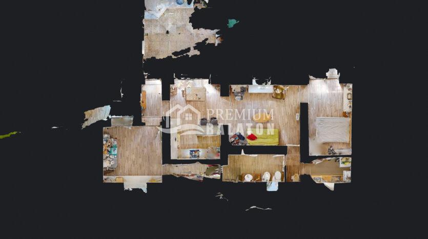 Top-down view of a multi-room home floor plan with wooden floors and scattered furniture; dark background behind the layout.